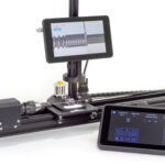 A benchtop coil winder with video microscope showing would coil and angle of coil There is a color LCD touch screen console in the foreground.