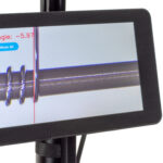 Video microscope showing magnified view of coil being wound over a mandrel. The winding angle is being measured and displayed on screen using computer vision of the edge of the wire.